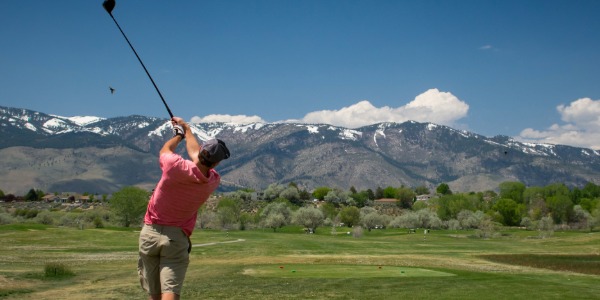 man golfing with mountains in background